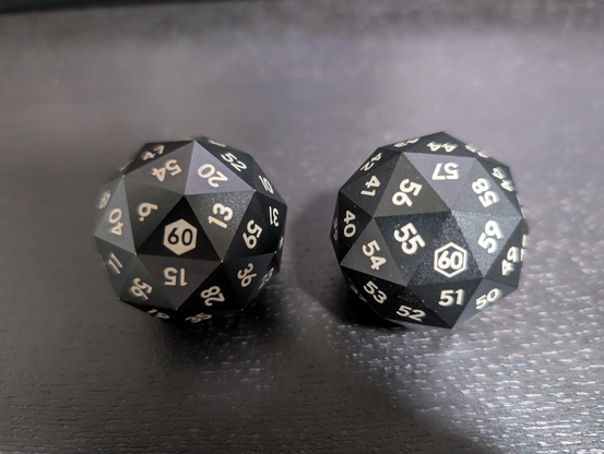 Photo of two d60 side-by-side. On the left, the numbers are uniformly but randomly distributed across the the faces. On the right, the numbers are numerically increasing in a counter-clockwise fashion across the faces.