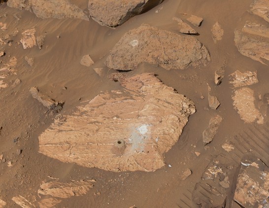 Two flat rocks on Mars with flat round abrasion patches and one deep core hole with a tailings pile next to it
