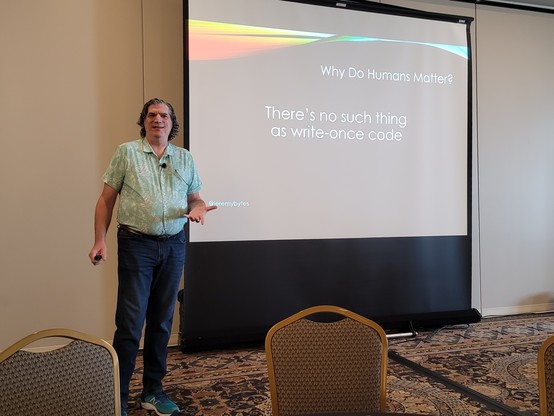An über nerd named Jeremy delivering a conference talk in front of a presentation screen 