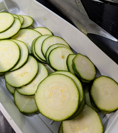Sliced zucchini in the catch container. Very evenly sliced and it took less time than taking out and setting up the mandolin did.

The slices will be salted and then spread on a tea towel to remove some moisture before seasoning and air frying.