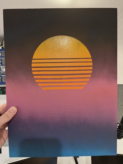 Artwork featuring a stylized sunset with a large yellow-orange sun, intersected by horizontal lines, set against a gradient background transitioning from a dark upper portion to purple and blue at the bottom.