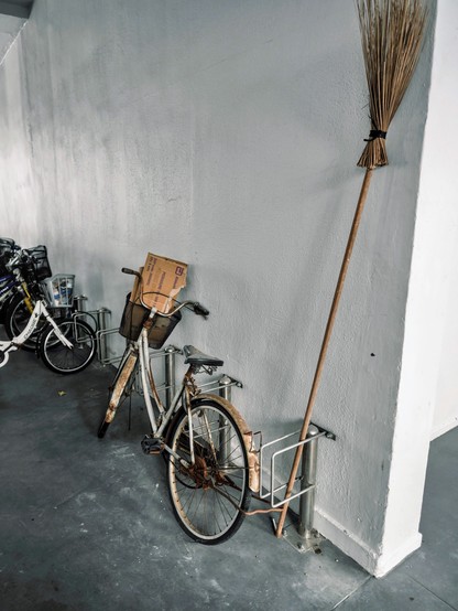 Rusty bicycle color matching a long wooden broom 