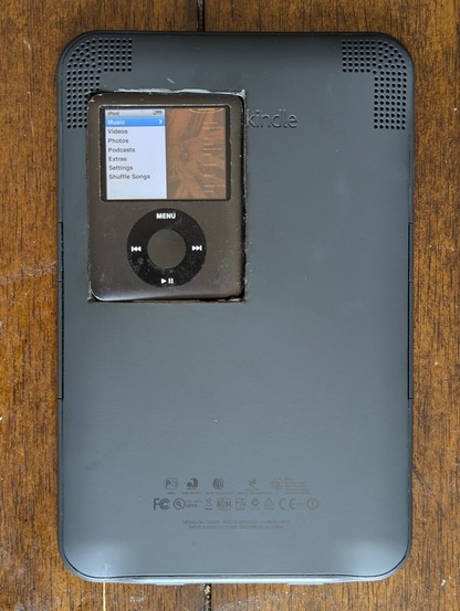 The back side of that same kindle... Holup, there's an iPod Nano 3rd Gen embedded into the top left corner.