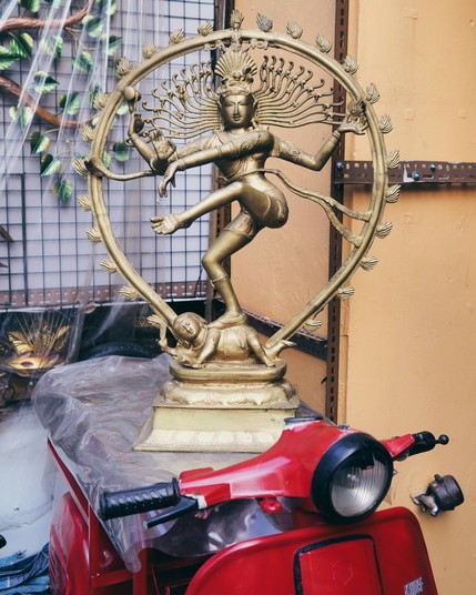 A Shiva statue on the back of a decorative red vespa moped.