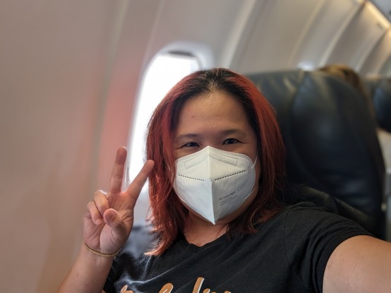 Selfie of Mariatta seated on an airplane wearing face mask