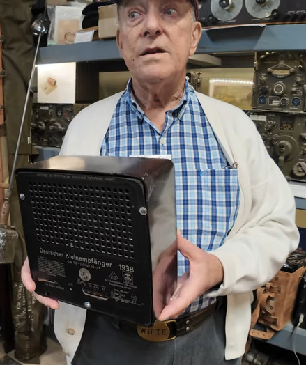 A museum spokesperson showing the rear of a radio given to citizens of Nazi Germany in WWII.

On the back are the words: 