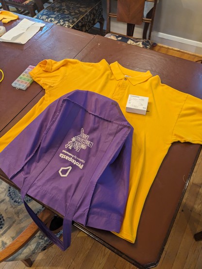 purple tote bag laying on top of a bright yellow collared shirt