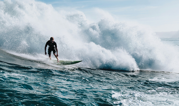 Person surfing in the ocean (© Photo by guille pozzi on Unsplash)