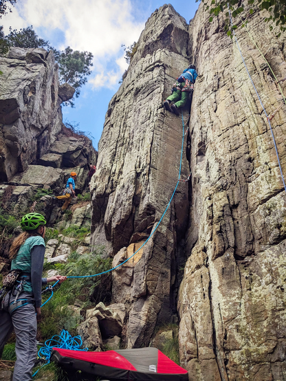 Rock climber ascending a prominent V shaped groove in a sandstone crag.