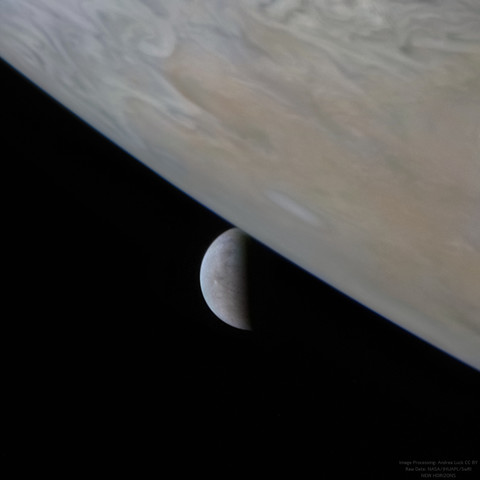 The icy world Europa, in a crescent phase, appears to be rising above Jupiter's swirling atmosphere.