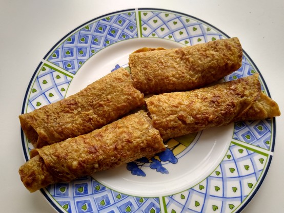 Soft rolled oatcakes on a plate, resembling a rolled up crêpe or pancake, but a darker savoury colour.