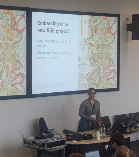 A woman with glasses presenting at the RSECon24. Behind her, on a large screen, is a slide titled 