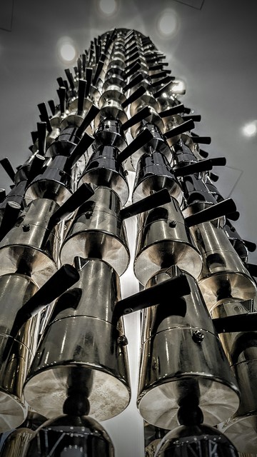 Black and white photo of a column made of shiny coffee makers