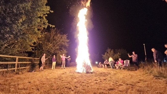 FootFest bonfire with on lookers basking in the heat of a burning Christmas tree which is sending flames about 10m into the air