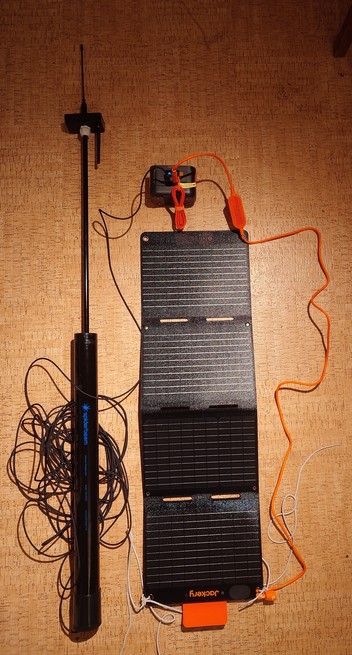 A Spiderbeam telescopic pole with a node box on the end connected to a solar panel and battery all lying on the floor