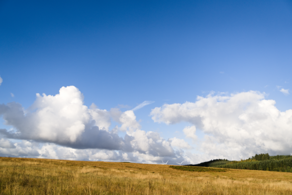 Countryside view with mostly blue sky, but a few clouds lurking above the horizon.