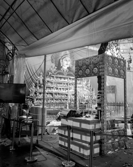 Photo of tent extension at Hindu temple after closing hours, showing multiplier tiers of statues of Hindu deities figures 