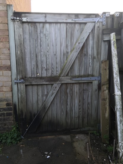 Old sagging wooden gate that was mounted backwards and/or the diagonal bracing was merely decorative, has been fitted with an anti-sag kit ordered off the Internet. It consists of a turnbuckle and steel rope that is tensioning the diagonal from top right (where the top gate hinge connects to the post) and lower left corner that would have dragged along the ground.