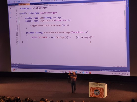 Jeremy Clark speaking in front of a movie theater screen showing his code. He looks so small inside the huge room.