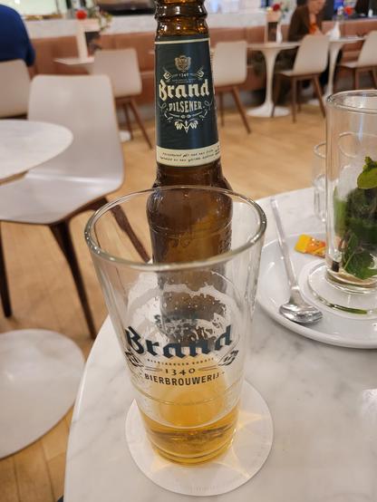 A glass of beer, mostly gone, poured from a bottle. Both the bottle and glass are labeled 