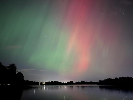 Red and green aurora over a lake