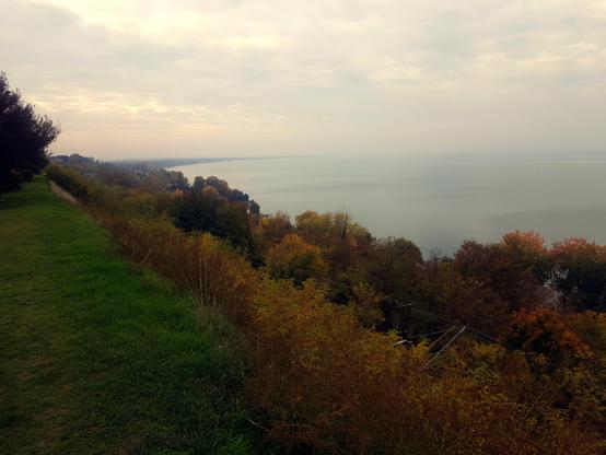 Balatonvilágos at lake Balaton. The upper shore with trees under my feet where the train tracks are going. To the right there is the Balaton lake covered with clouds.