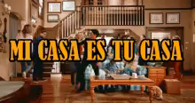 a group of people are gathered in a living room with the words mi casa es tu casa above them