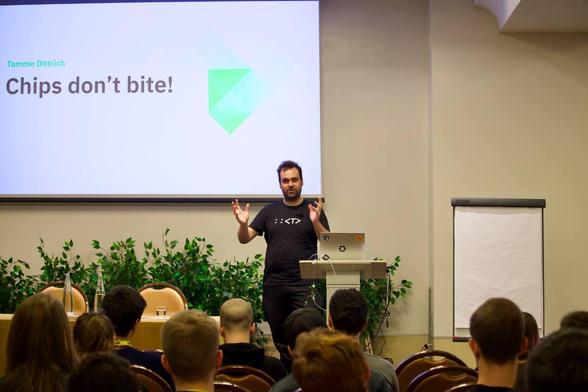 Picture shows Tamme on stage at RustLab 2024 with the title slide of Chips don't Bite behind him.