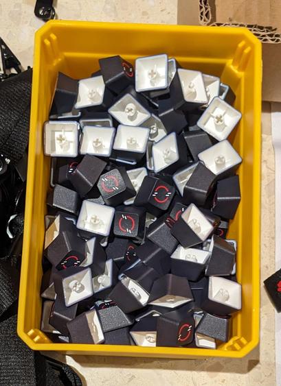 a yellow plastic bin full of keycaps with the openshift logo on them