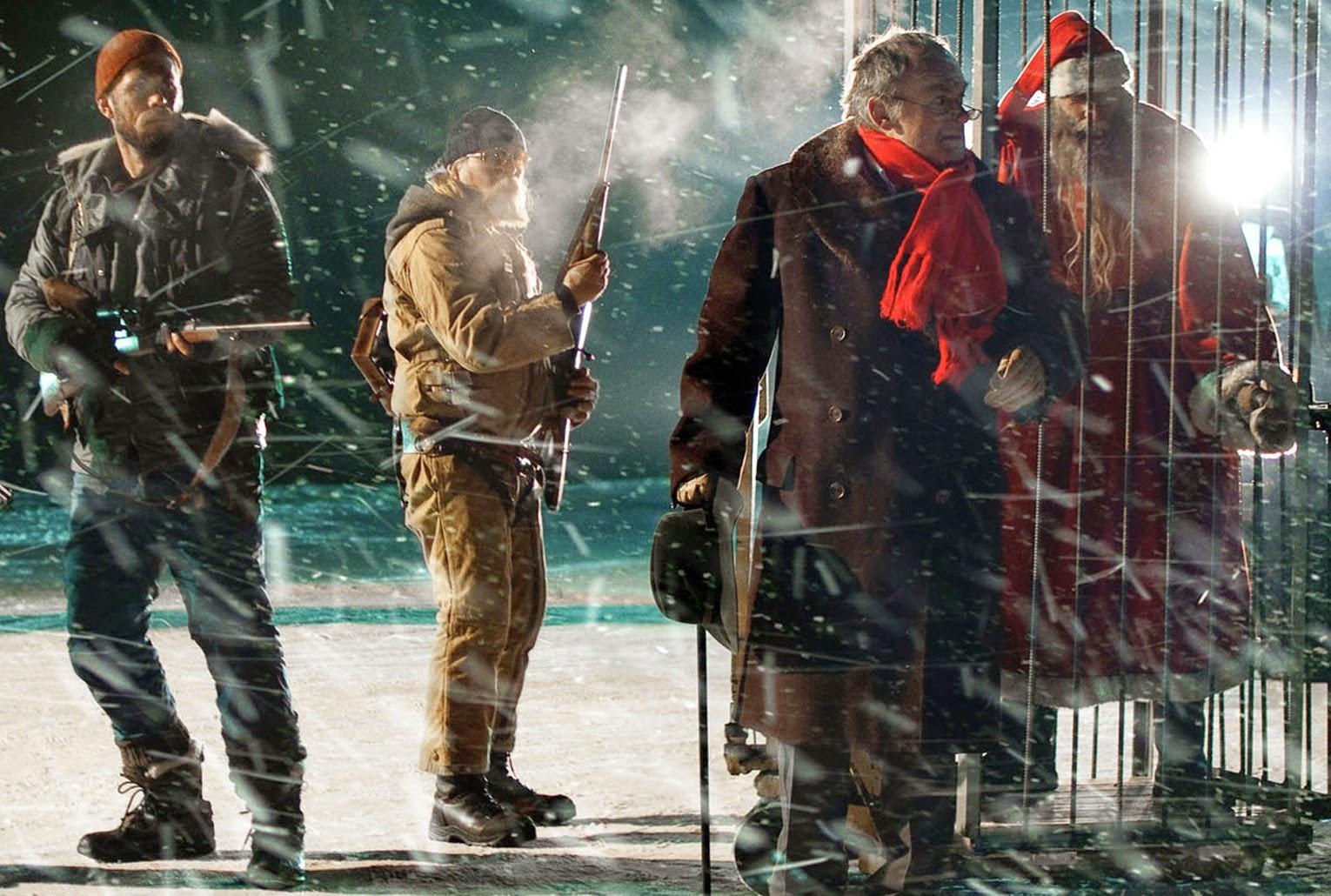 A sinister looking character in a Santa costume, who maybe isn't the real Santa, is locked in a cage and guarded by men with rifles.