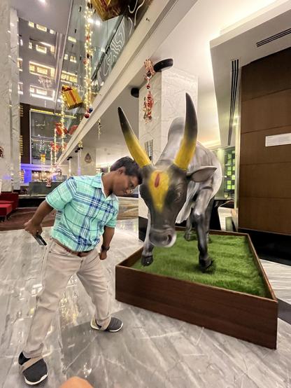 me a dwarf person headbutting a jallikattu bull statue
