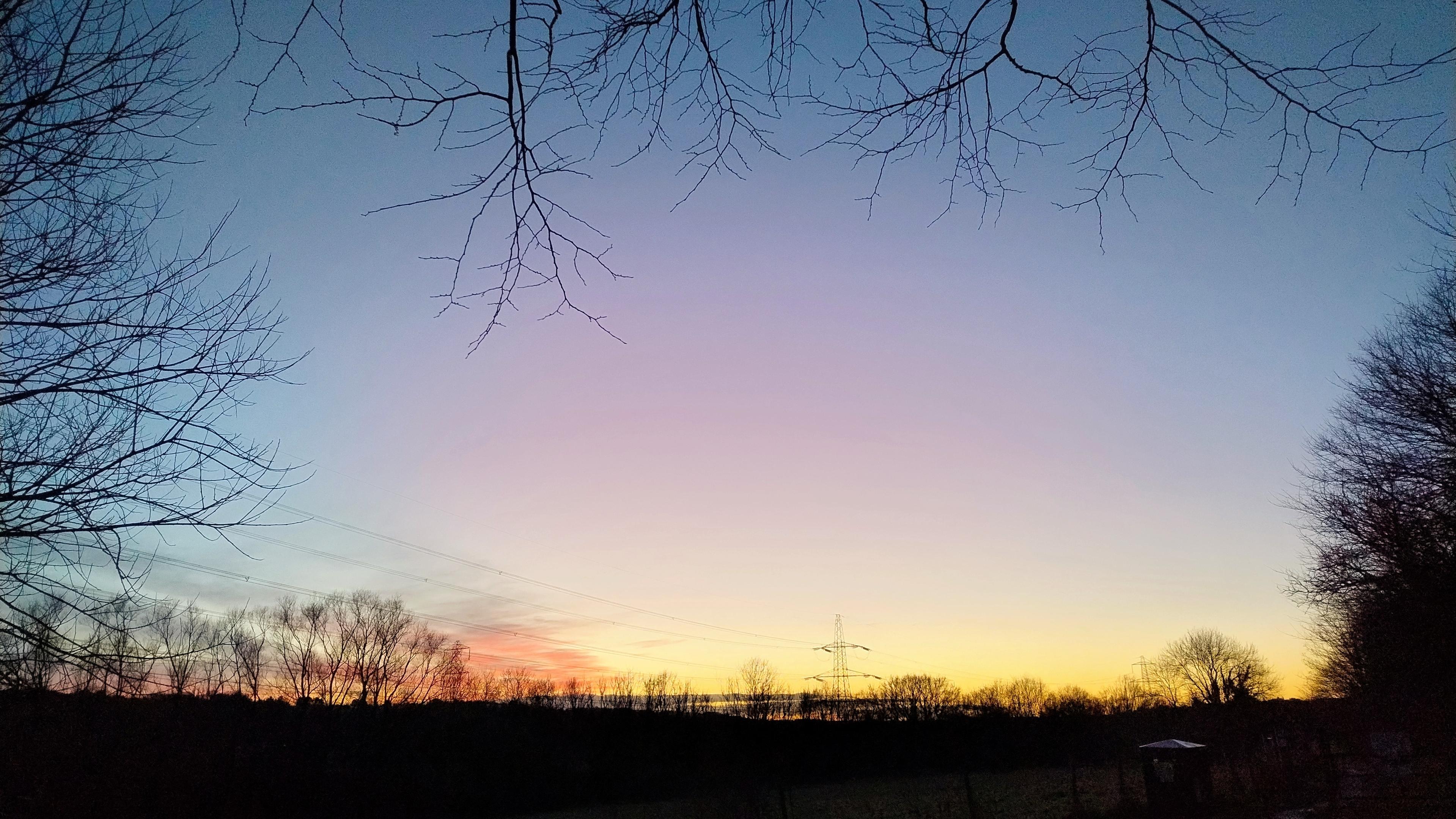 Clear post-sunset sky, an orange glow along the horizon becomes a pink glow in the centre of the frame.