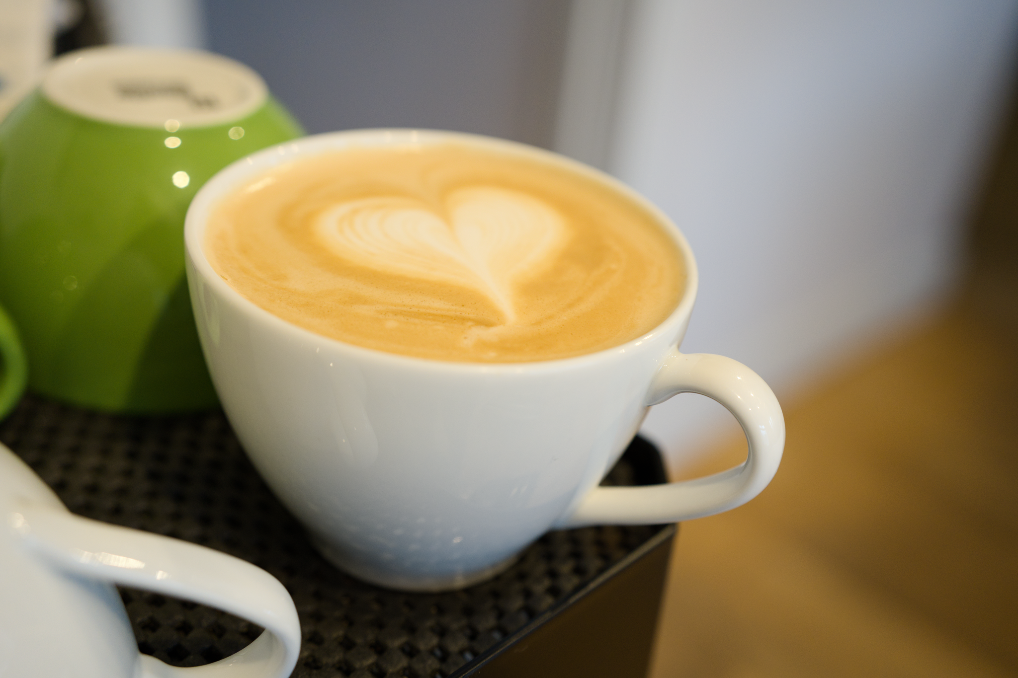 A flat-white on the cup warmer of an espresso machine. Moderately respectable heart shaped pattern in the milk!