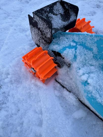 A close-up photo of the rear paddle wheels of the OpenRC F1 car showing the chunks that have been taken out of the paddles, likely by rocks under the snow in the driveway.