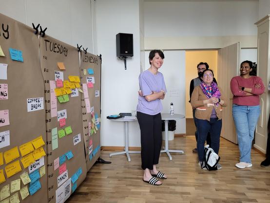 The Open Science Retreat board showing the schedule and people standing next to it