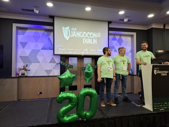 DjangoCon Europe main stage with 3 organizers, and ballons in a shape 20 to calebrate Django's 20th birthday.