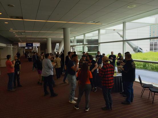 PyCon US 2025 sprinters standing around two tables, eating pizza