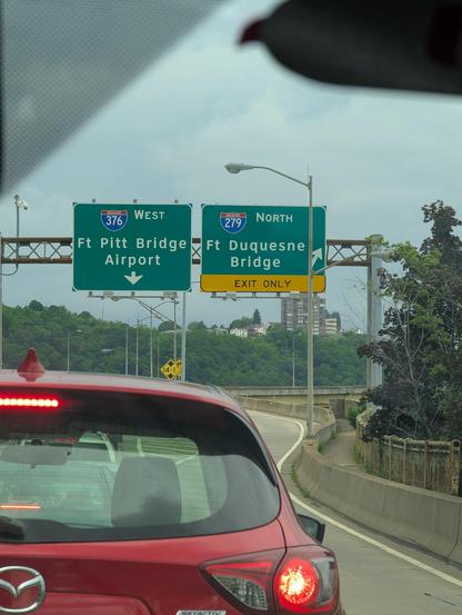 Photo of interstate signs indicating the route to I-376 West toward the Pittsburgh airport. The photo is taken from inside of a car sitting in traffic.