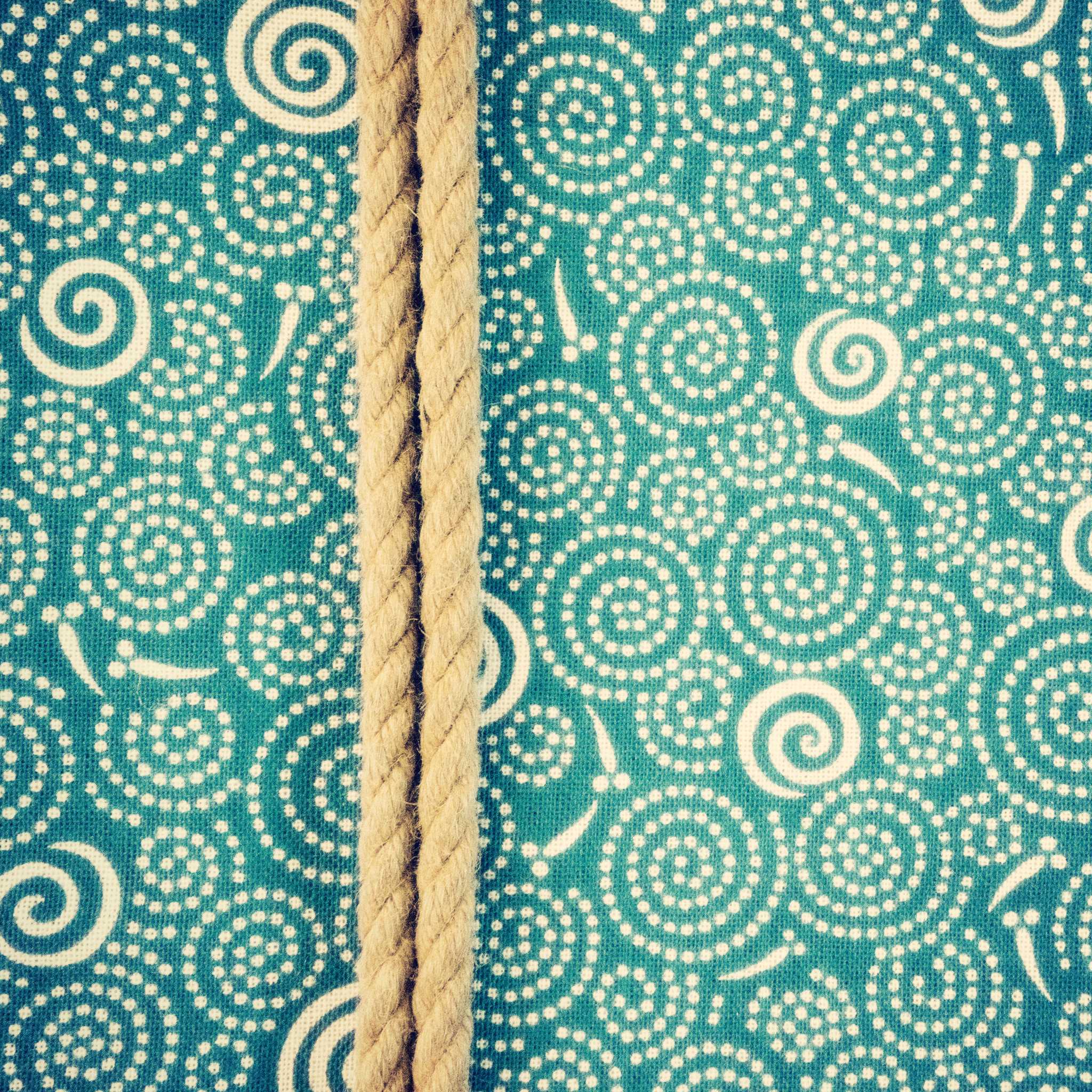 An aqua green-blue Japanese facecloth depicting swirls (probably where raindrops are landing on the water?) and slightly abstract fish swimming in pairs.