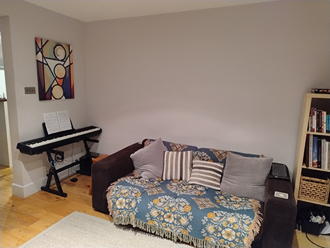 A blank living room wall above a sofa. The piano has one of my older canvases - an abstract I call