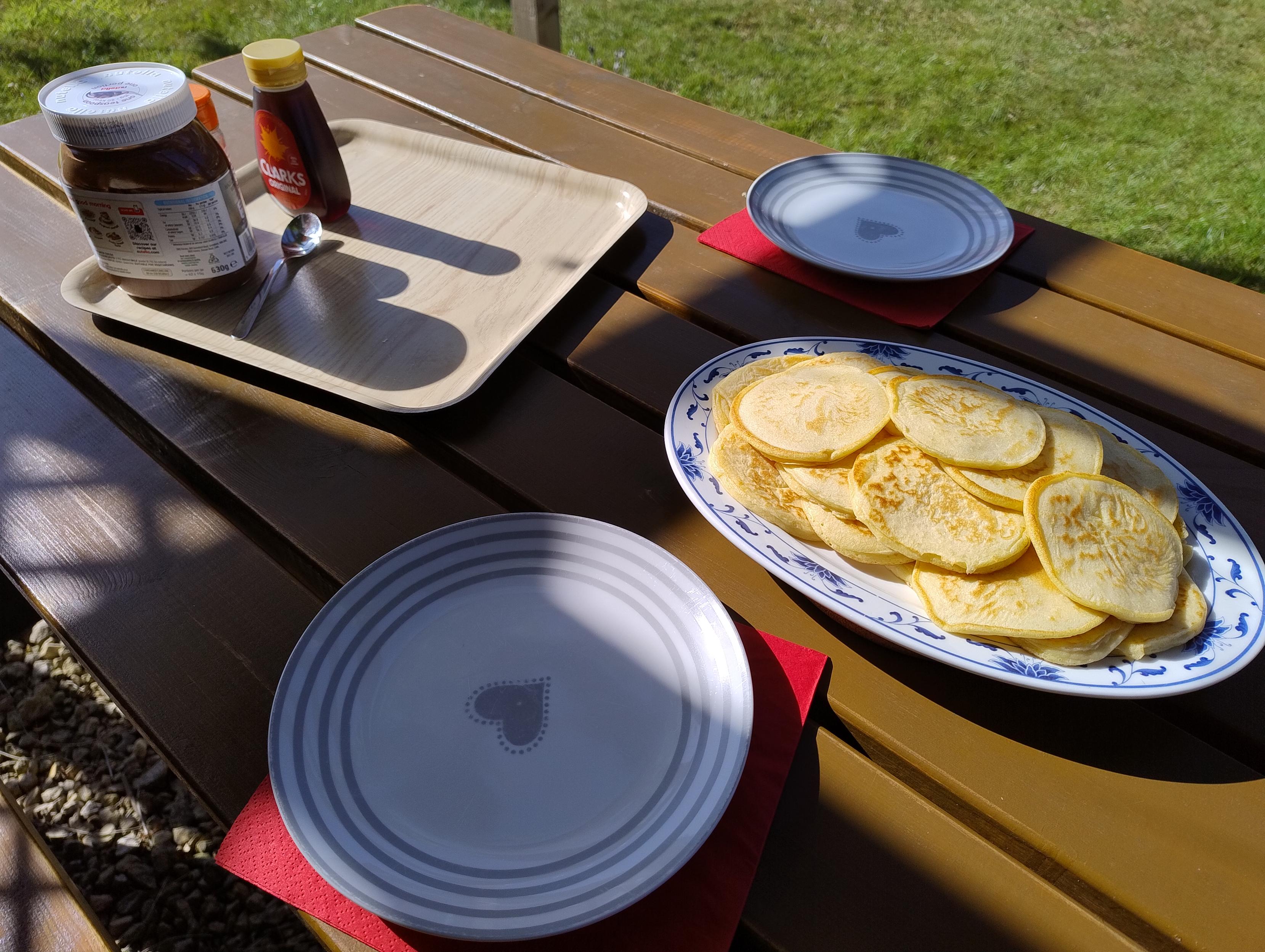 Plate of pancakes (some might call them drop-scones) on a sunny picnic table.