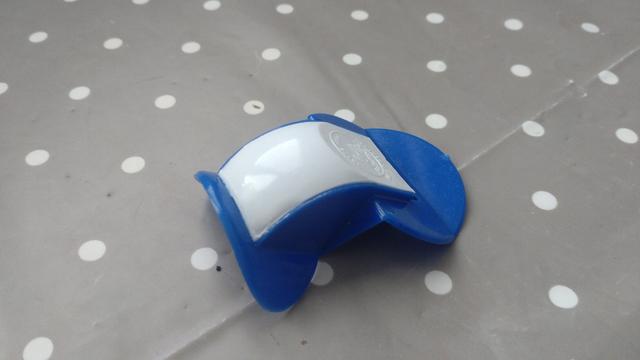 A blue/white plastic thing with a curved form bulging upwards, maybe 7cm diameter