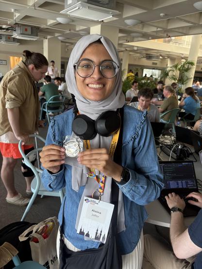 First time BeeWare contributor Alaina Jaffer holding their BeeWare challenge coin.