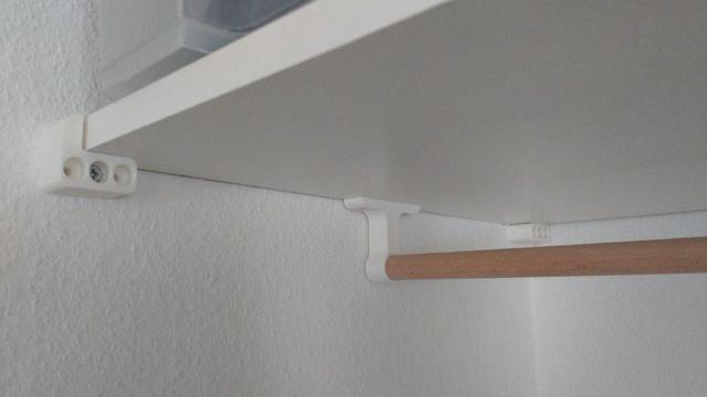 A "wardrobe" with a white plate below which there is a wooden bar to hang jackets etc. 3D printed brackets hole everything together.