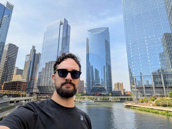 People taking a selfie with a river and skyscrapers in the background