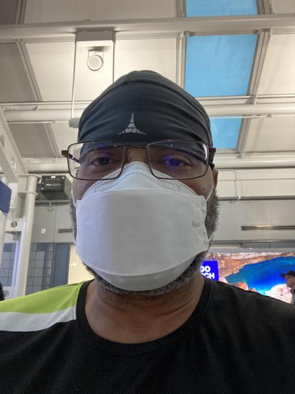 Headshot of Kojo at ORD airport. He’s in one of his signature skullcaps (gray) and the bright green shoulder of his Houston Outlaws OWL jersey is visible. He is wearing a mask.