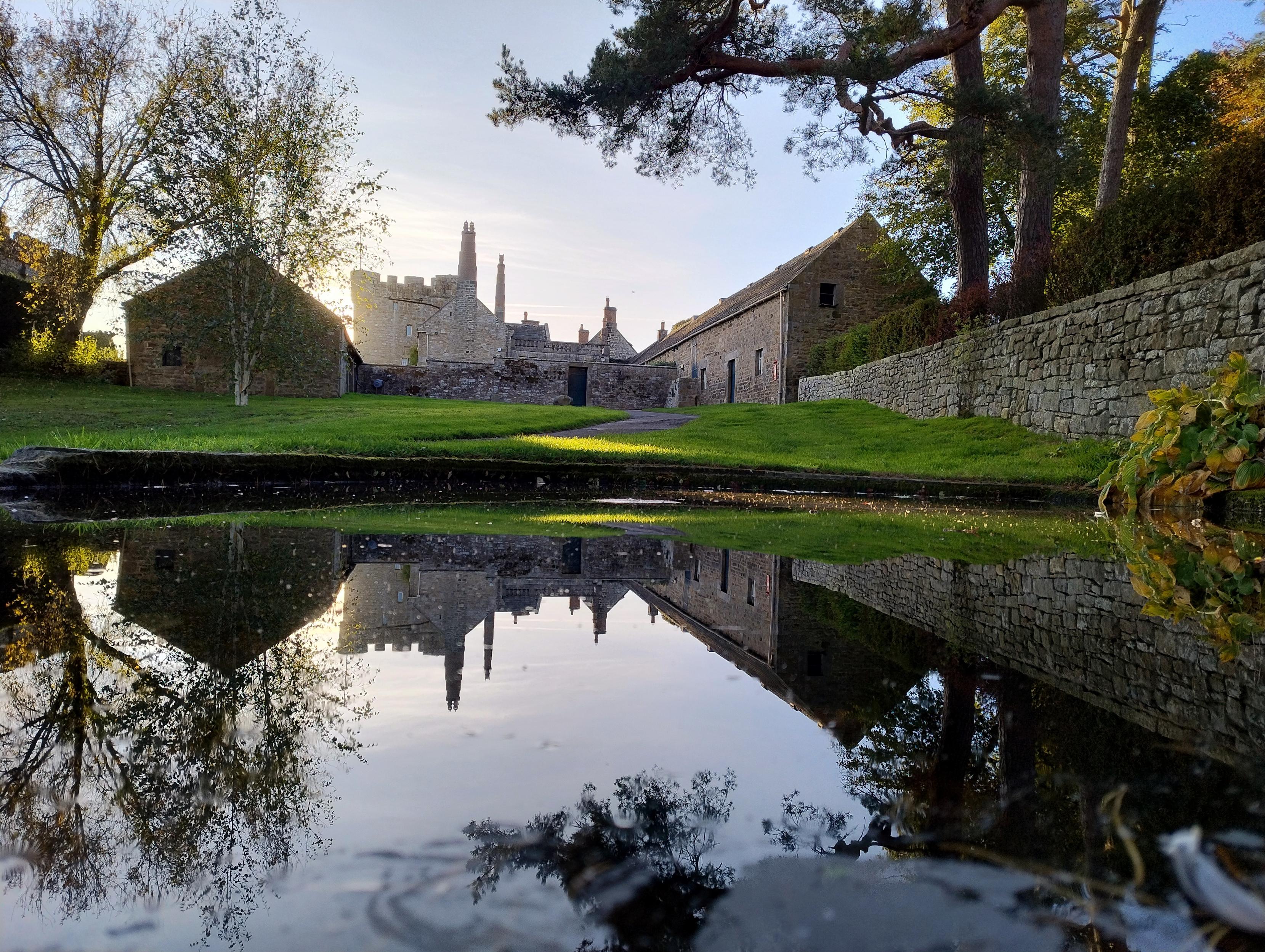 Reflection of a castle (fortified manor house) reflected in a small pond.