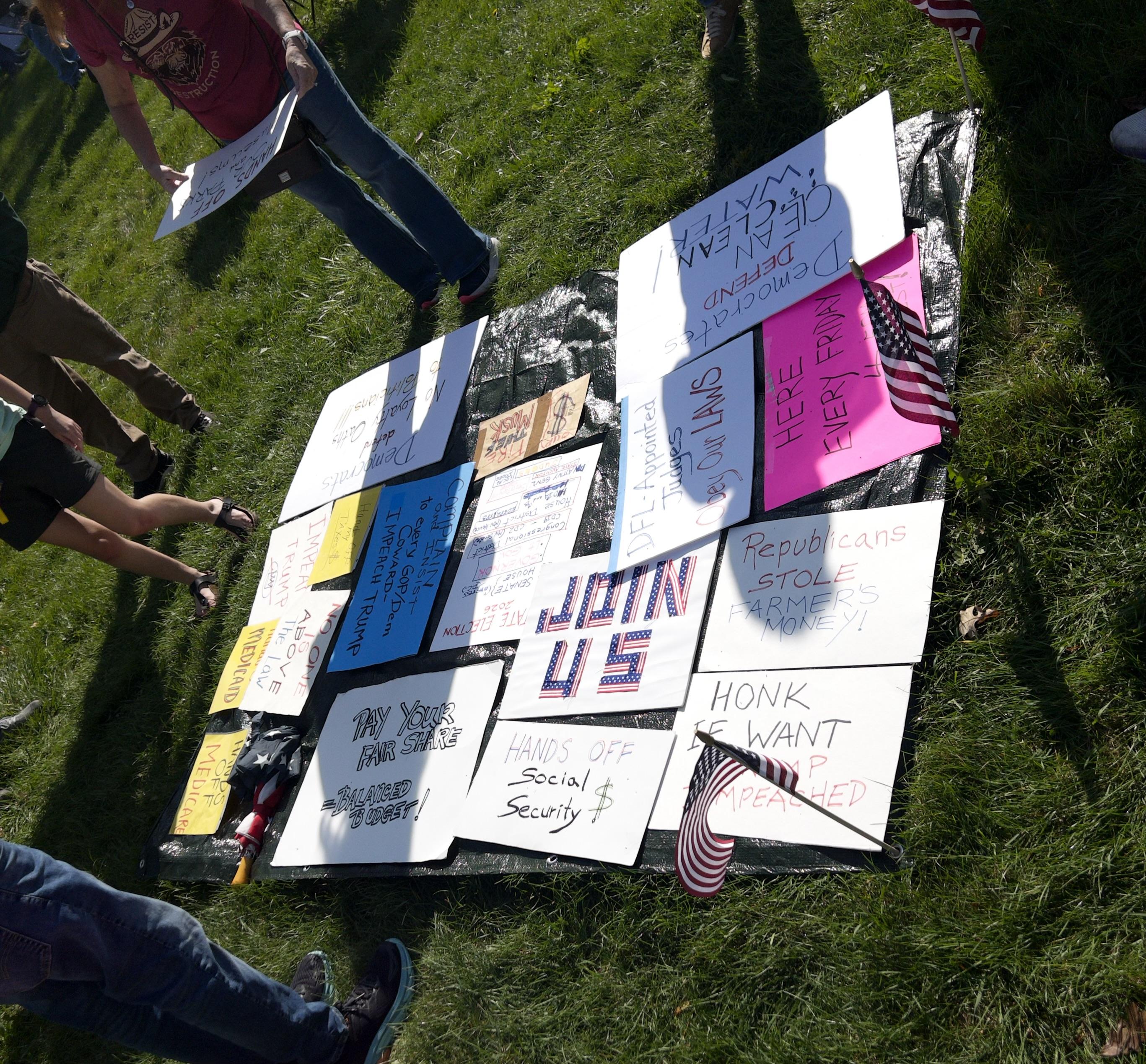 A collection of political signs arranged neatly on the ground.
