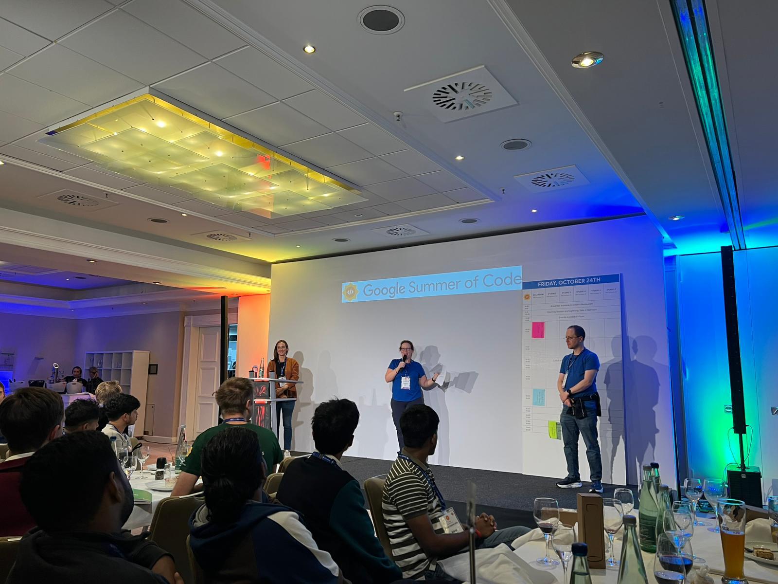 Three Mentor Summit organizers on stage introducing the event