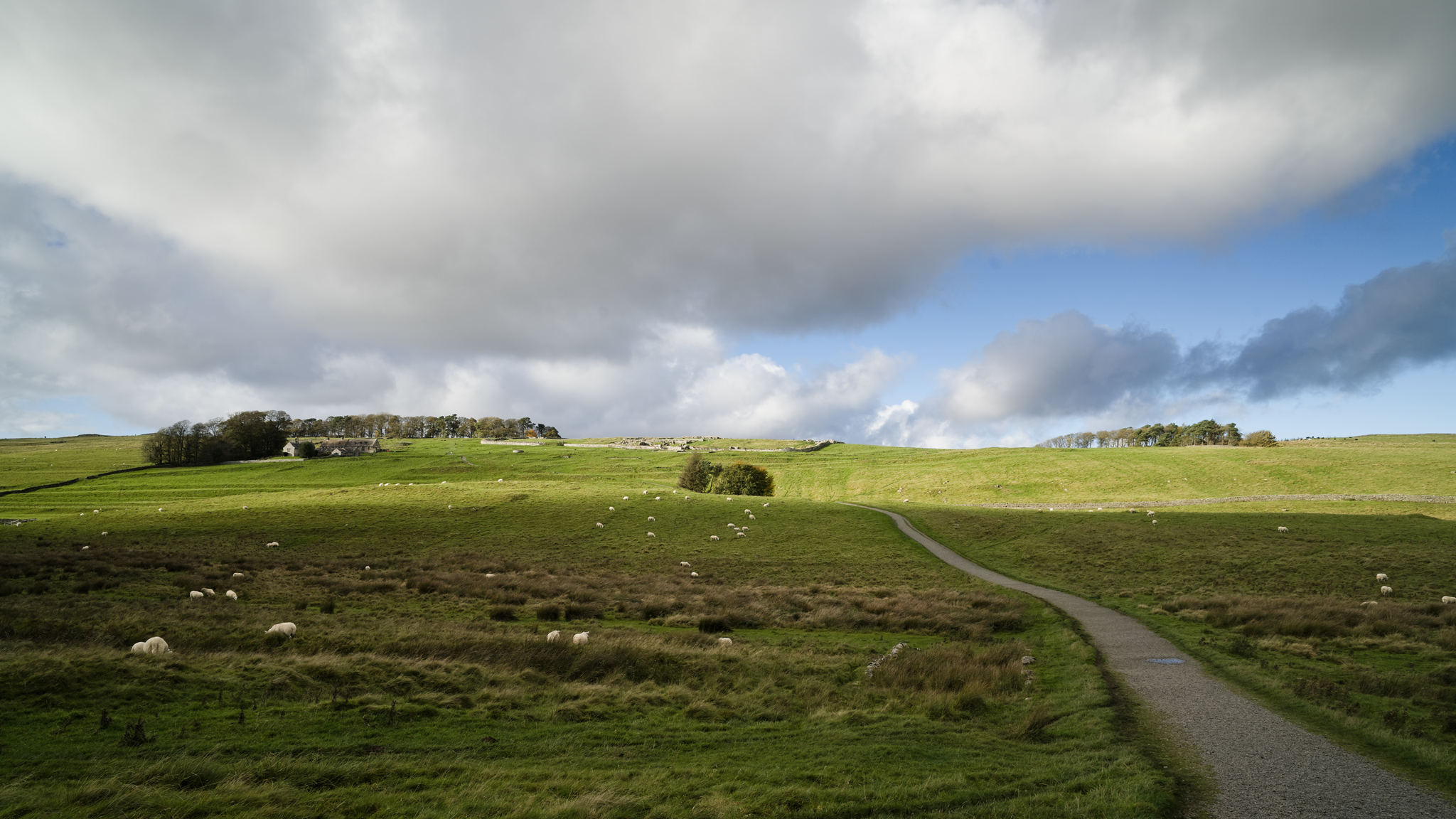 View of a hilltop fort in open countryside, under dramatic skies.